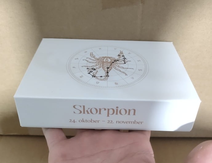 Hvid æske med stjernetegnet Vædderen, selvom æsken viser Skorpionen.