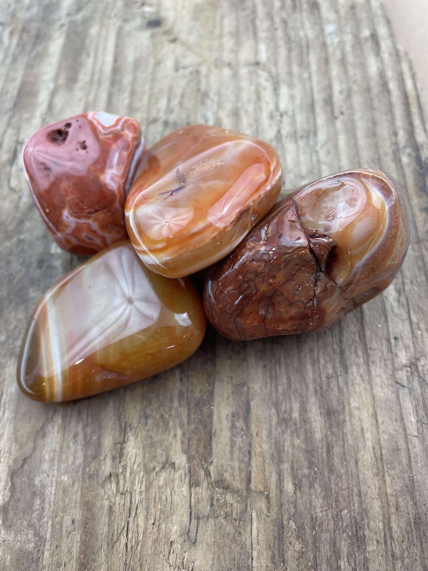 Fire smukke Agat Bahia sten i varme nuancer ligger på et træbord.