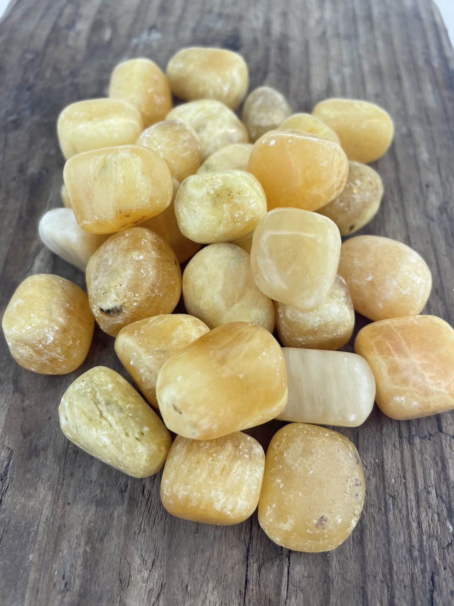 Polerede Gul Aragonit-sten samlet på en træoverflade.