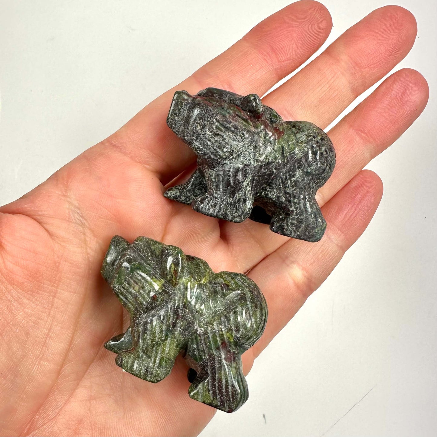 To små bjørnefigurer lavet af Drageblod sten i en hånd, visende deres detaljerede udskæringer.