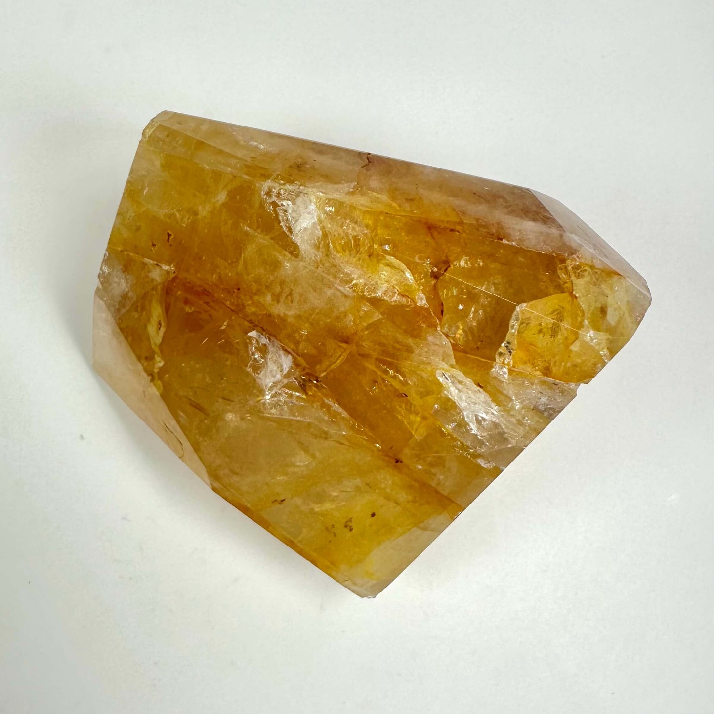 Golden healer krystal i fri form mod hvid baggrund, med gyldne nuancer og naturlige markeringer.