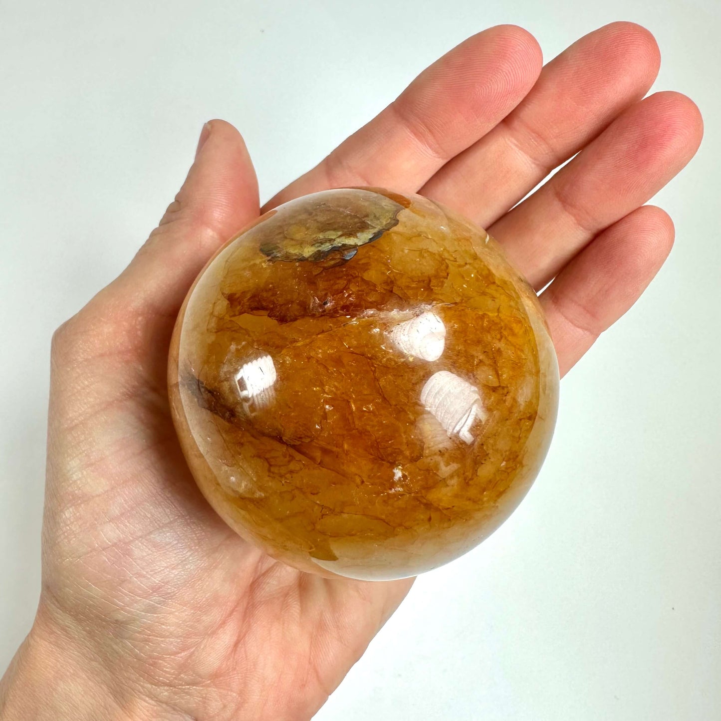 En hånd holder en Golden healer kugle med gyldne nuancer.