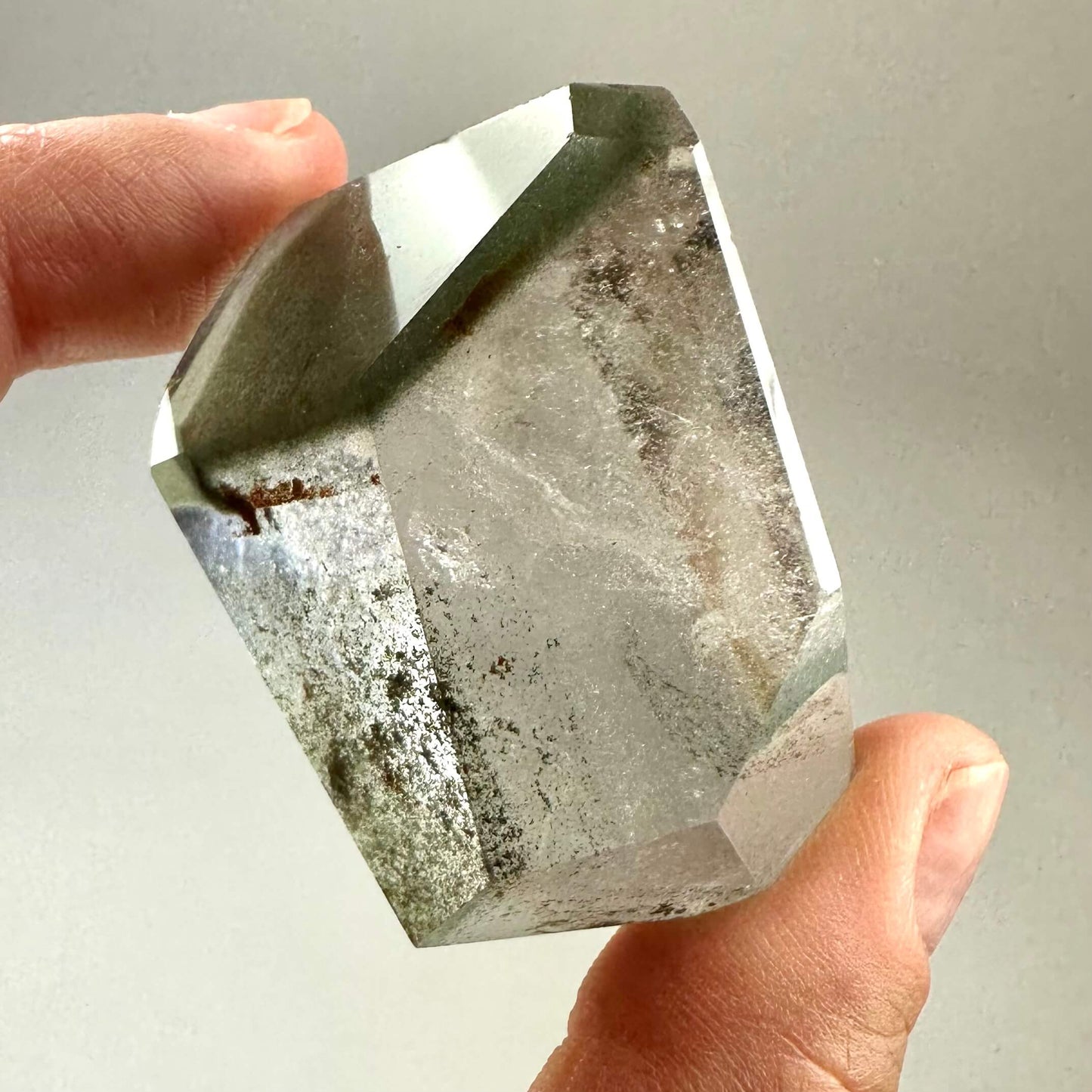 Fingers holder en stor, klar Fantomkvarts krystal med flere indre lag og farveskift.