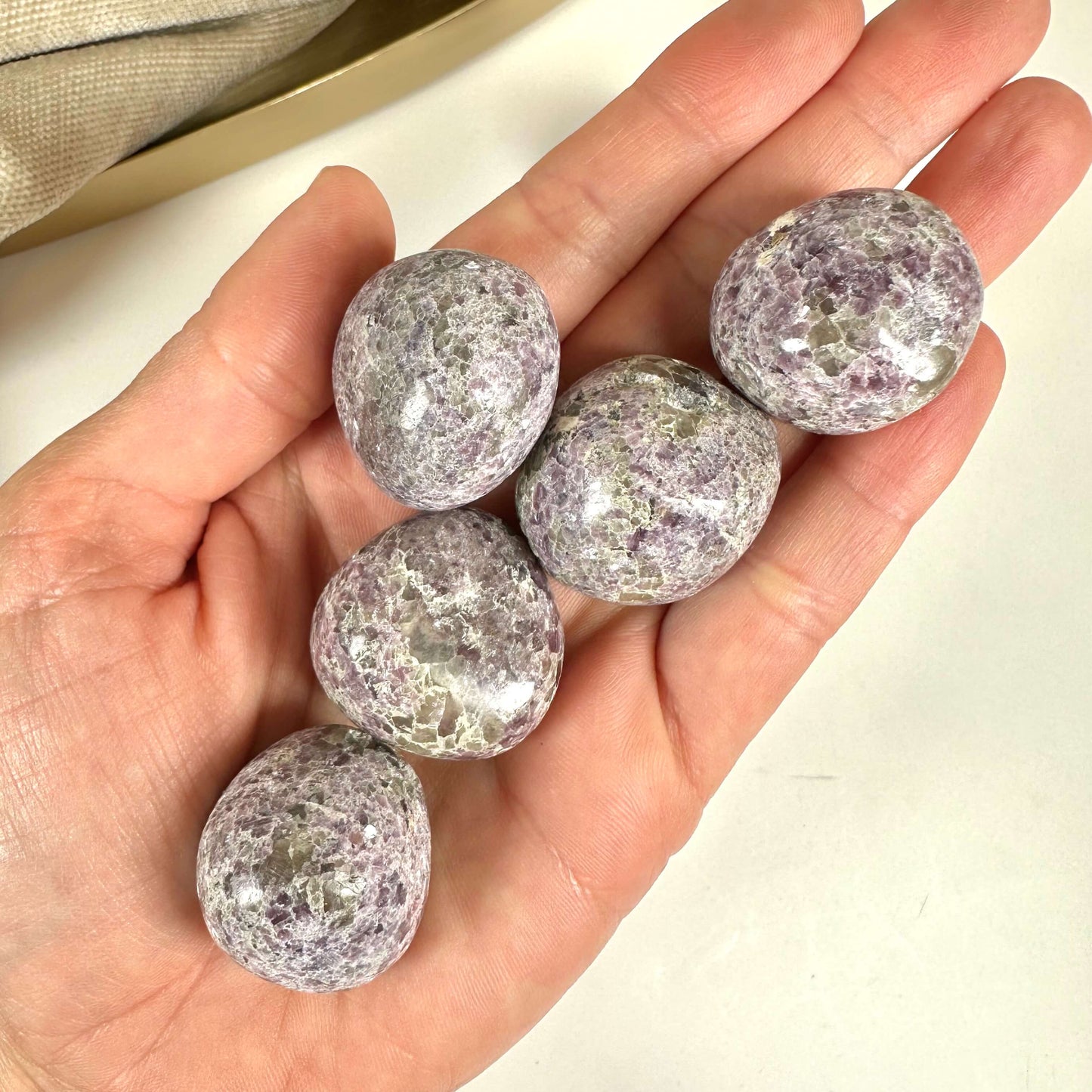 Hånd holder fem glatte sten af Lepidolit Mica XL i bløde lilla nuancer.
