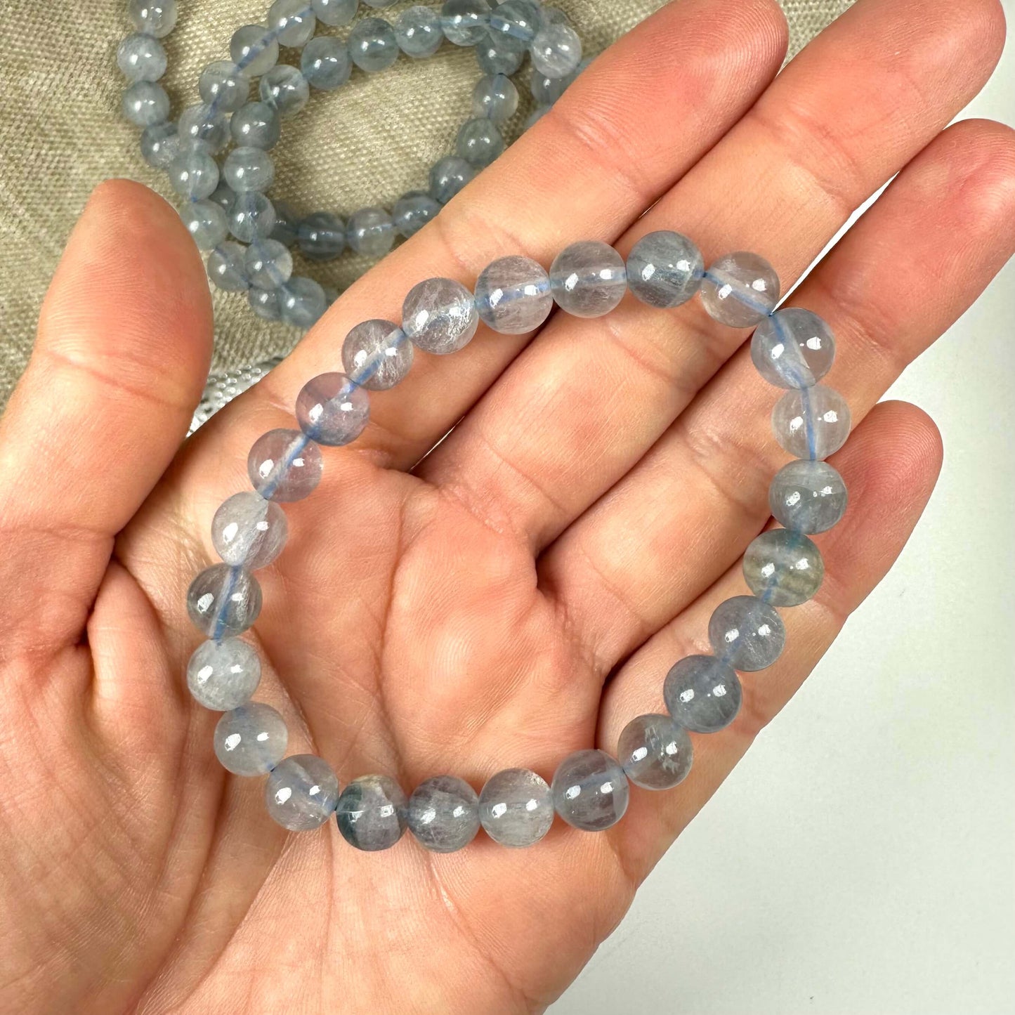 Blå fluorit armbånd 8mm i en hånd, med perler i en let gennemsigtig blå nuance.