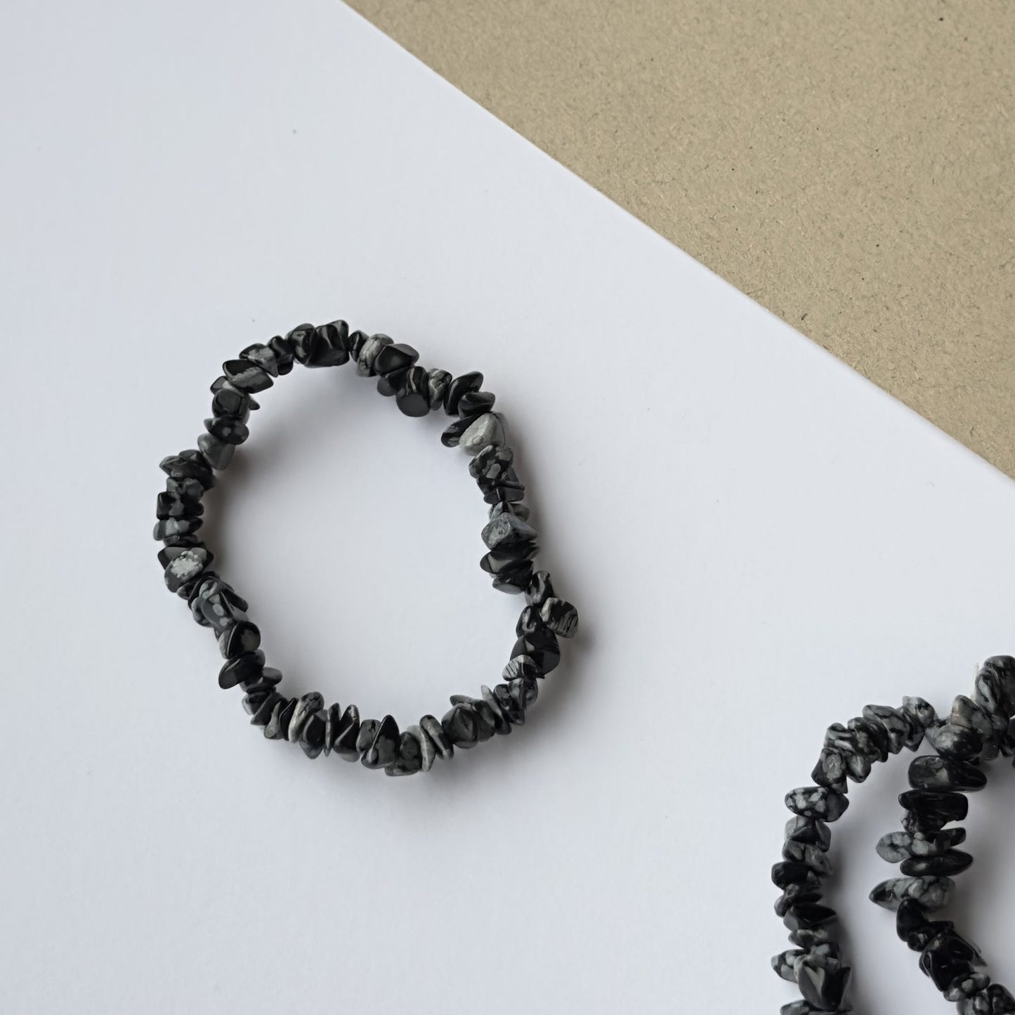 Obsidian Snefnug armbånd på hvid og beige baggrund med unikke sort-hvide sten.