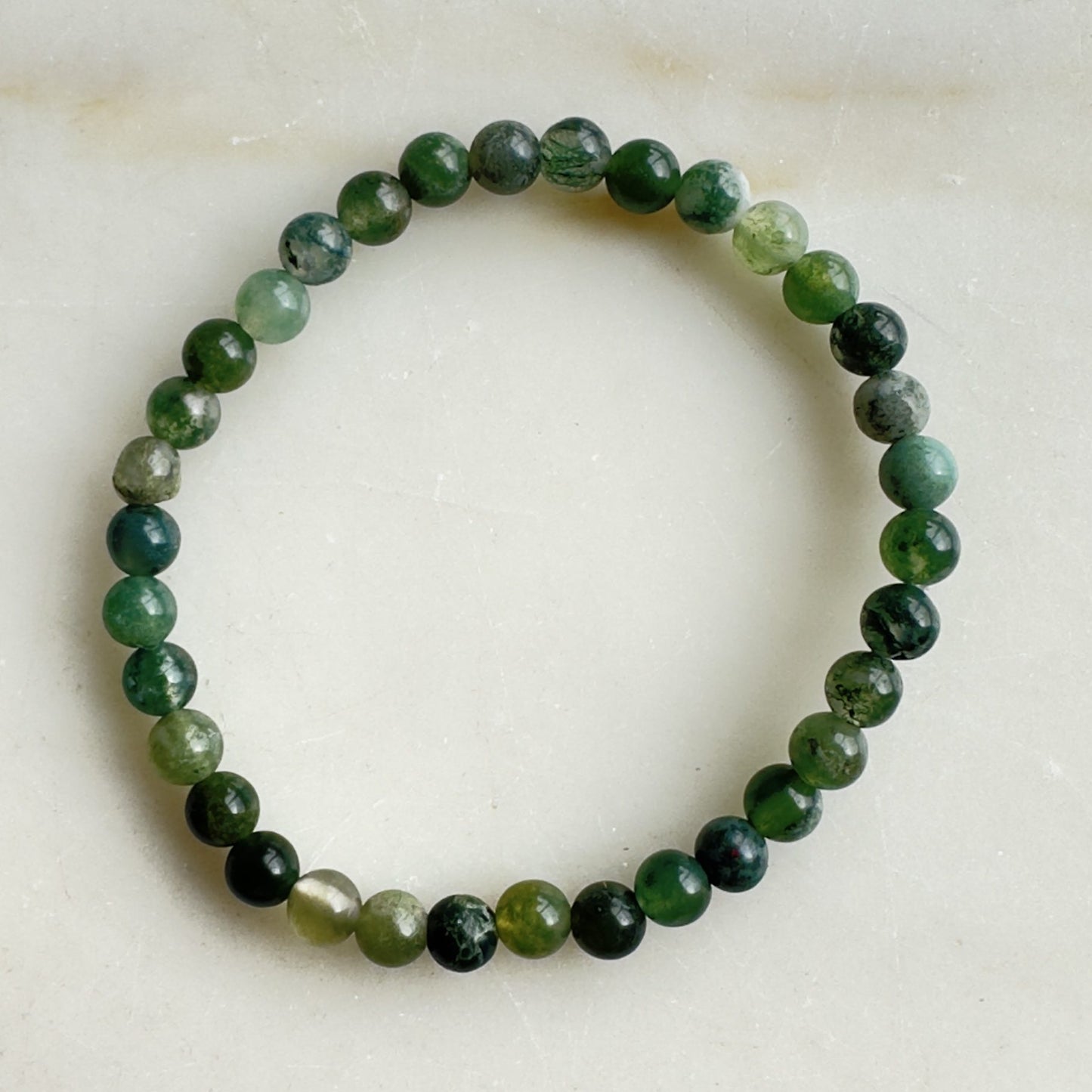 Mos Agat børnearmbånd med grønne perler på lys baggrund.