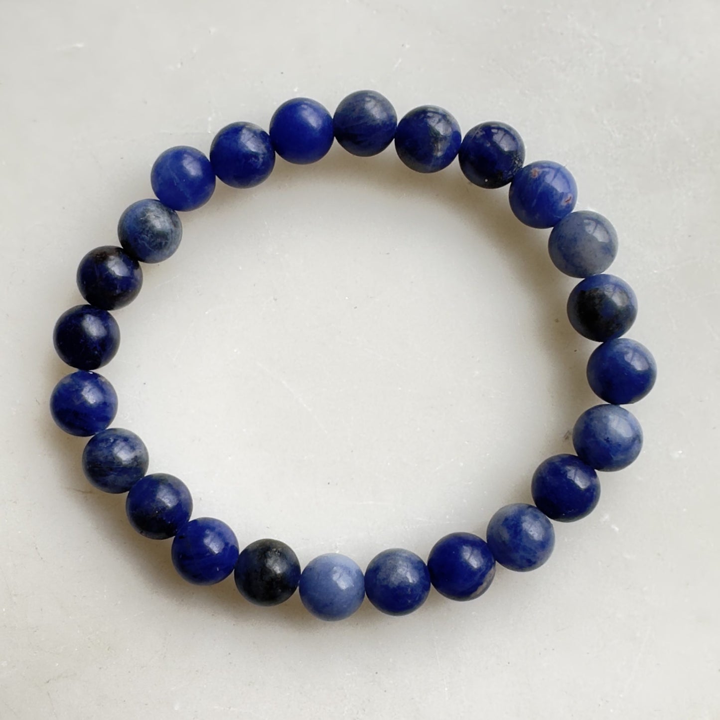 Sodalit børnearmbånd med blå perler på lys baggrund.