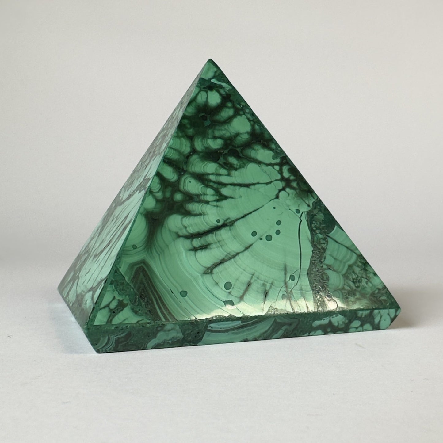 Malakit pyramide med mørkegrønne mønstre på en lys baggrund.