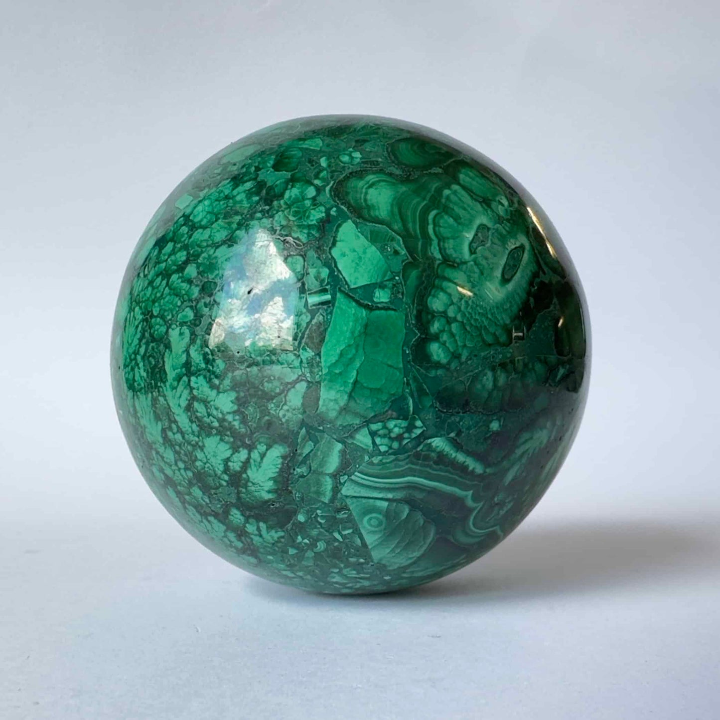 Malakit kugle med grønne og sorte mønstre på en lys baggrund.