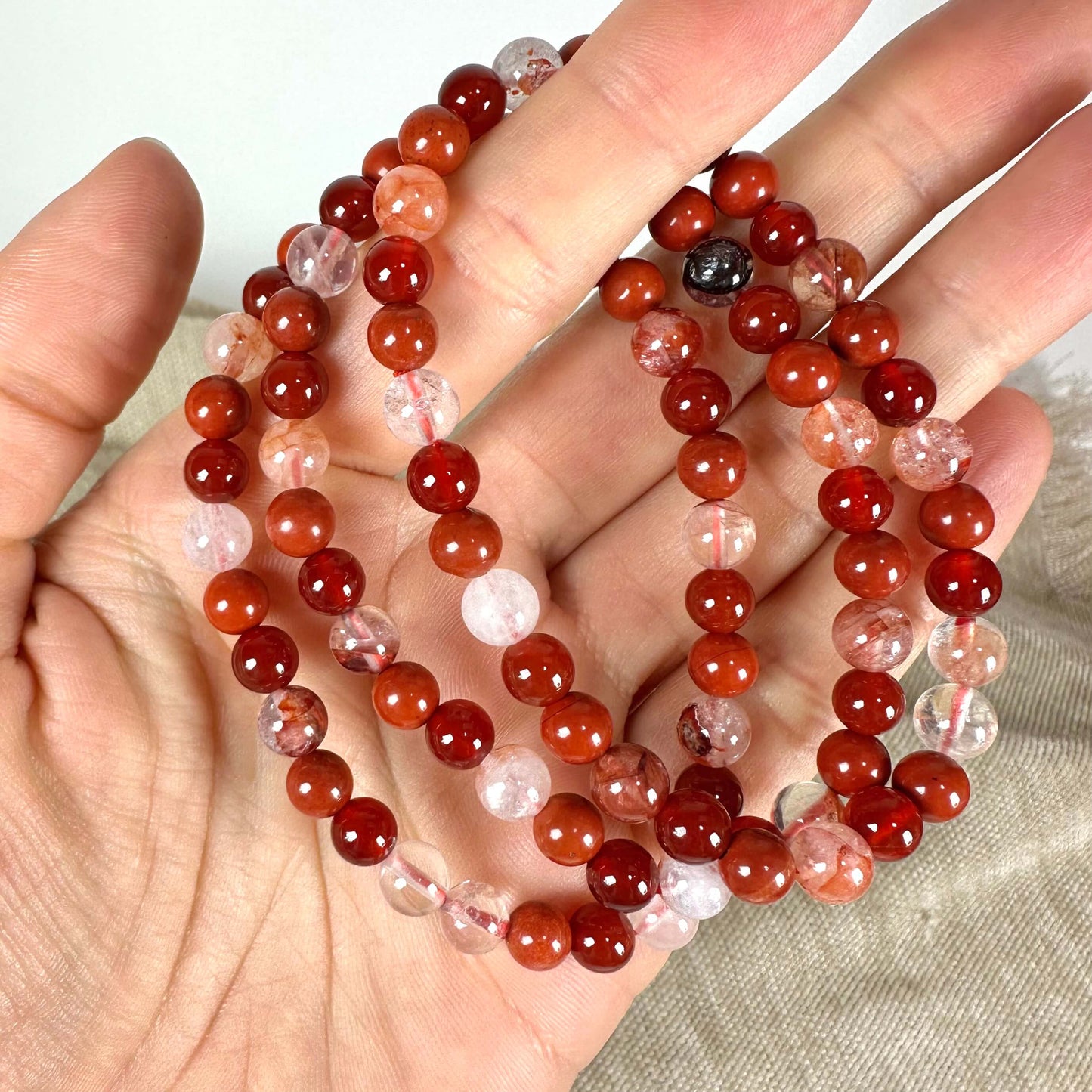 Hånd holder en halskæde af røde og gennemsigtige perler.