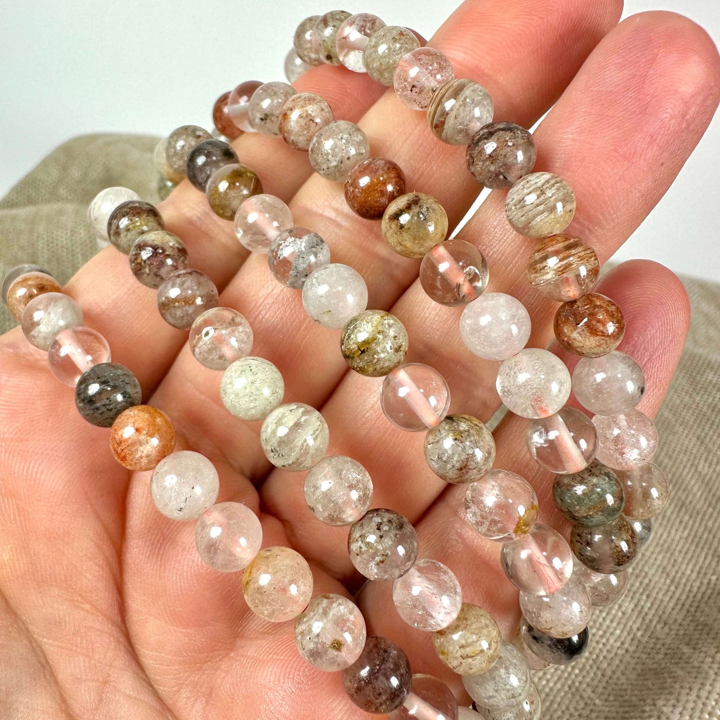 Perler af forskellige farver og mønstre holdt i en hånd.