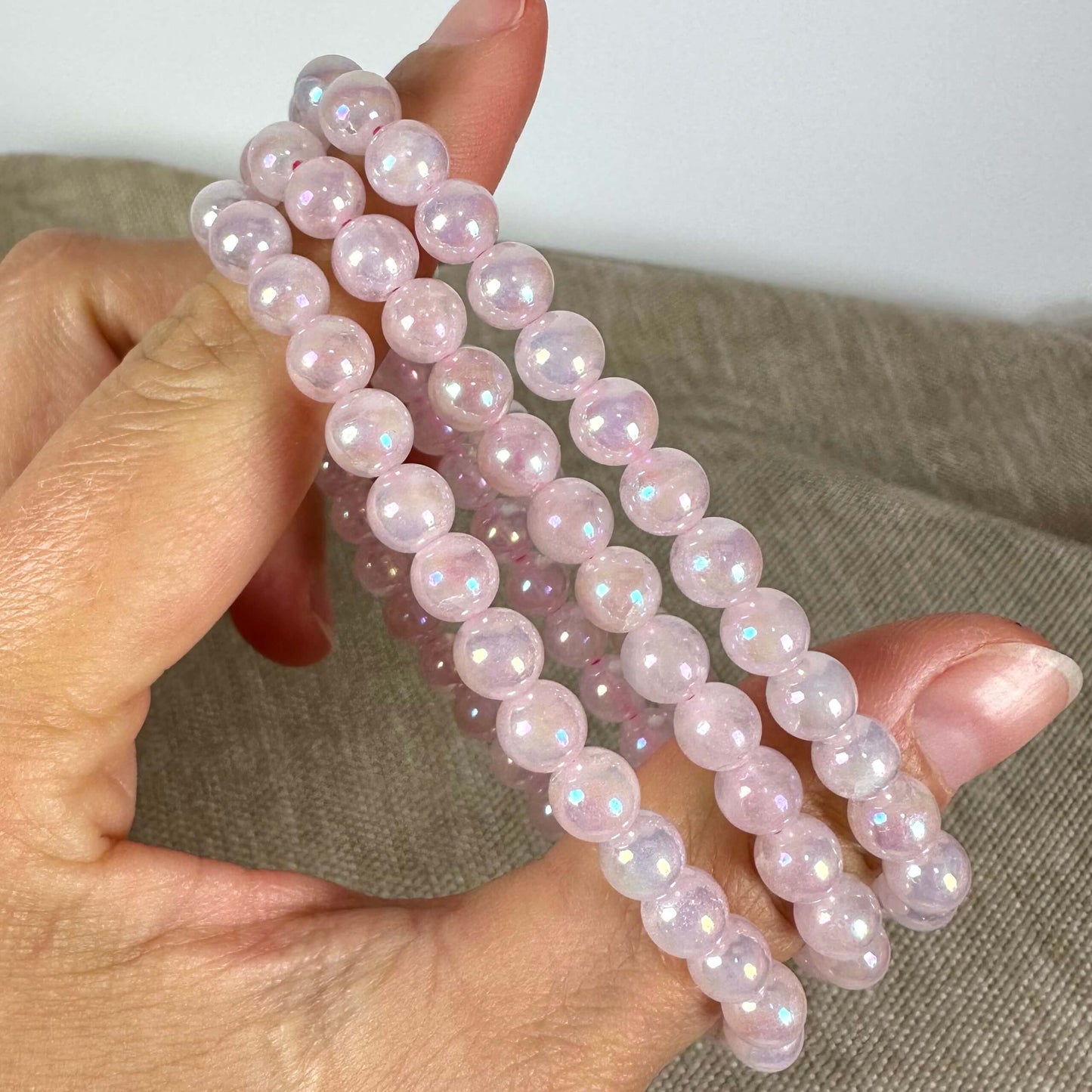 En hånd holder flere rækker af lyserøde perler på en beige overflade.