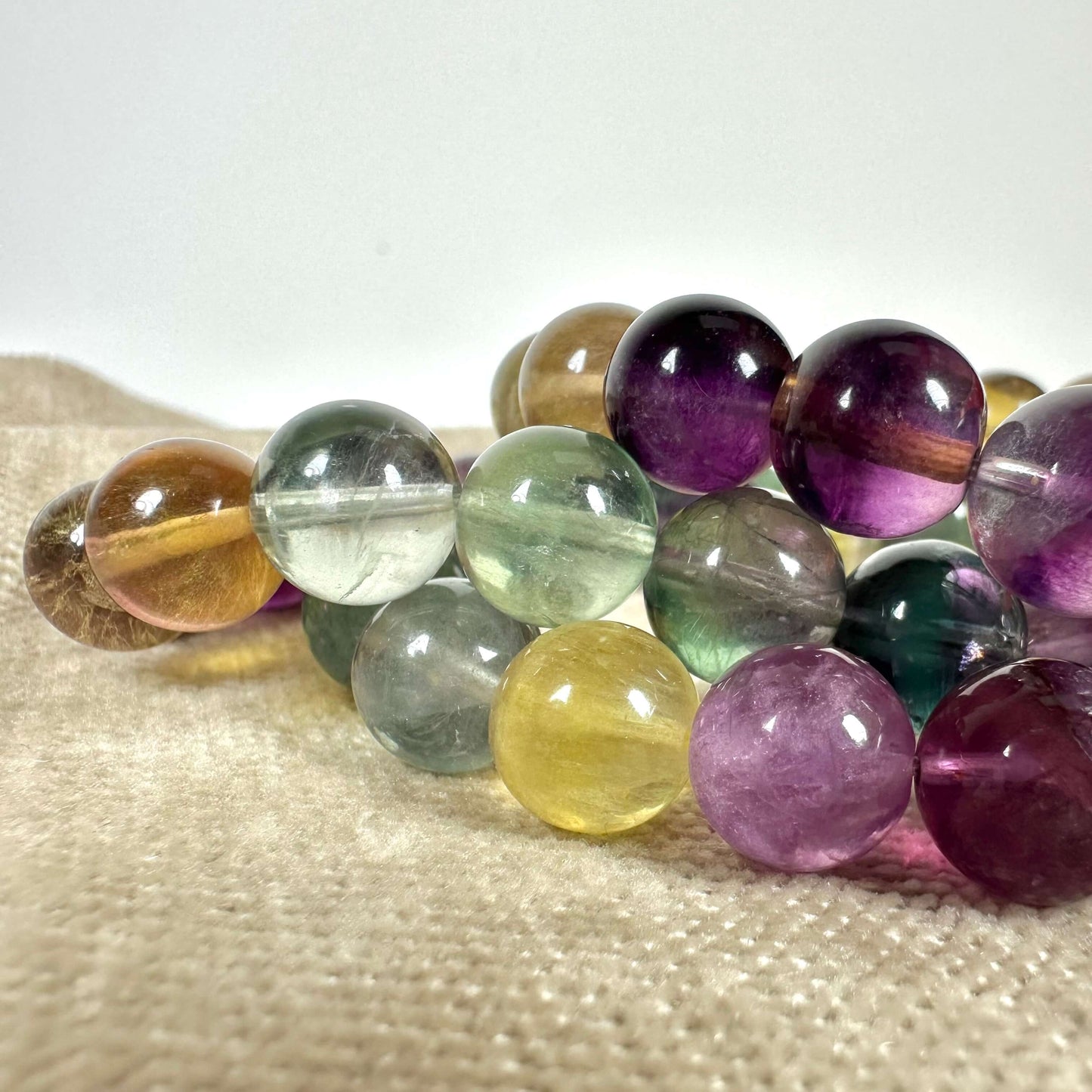 Perler i forskellige farver og størrelser på en beige overflade.