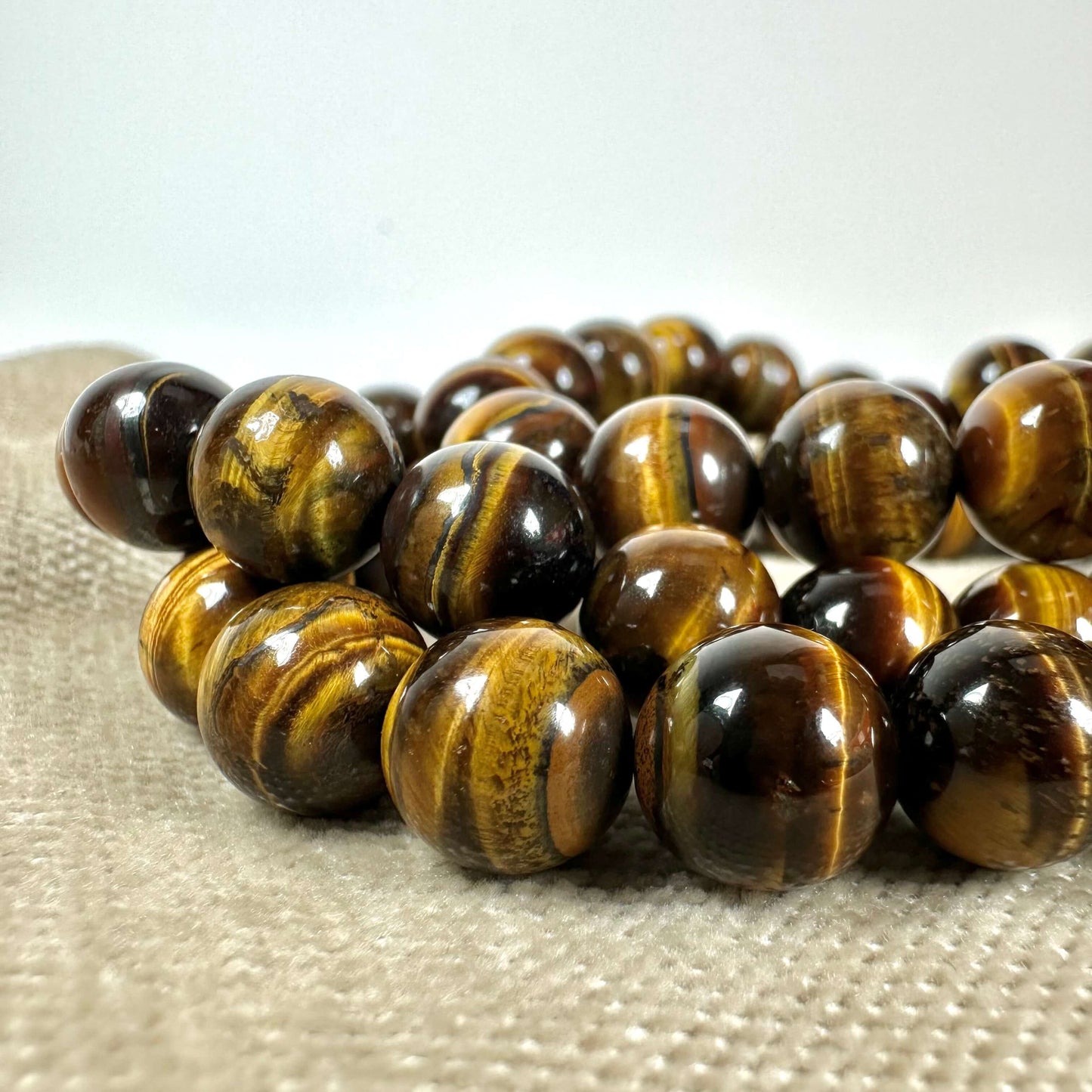 Brun og gylden tigerøje-perlekæde på en beige overflade.