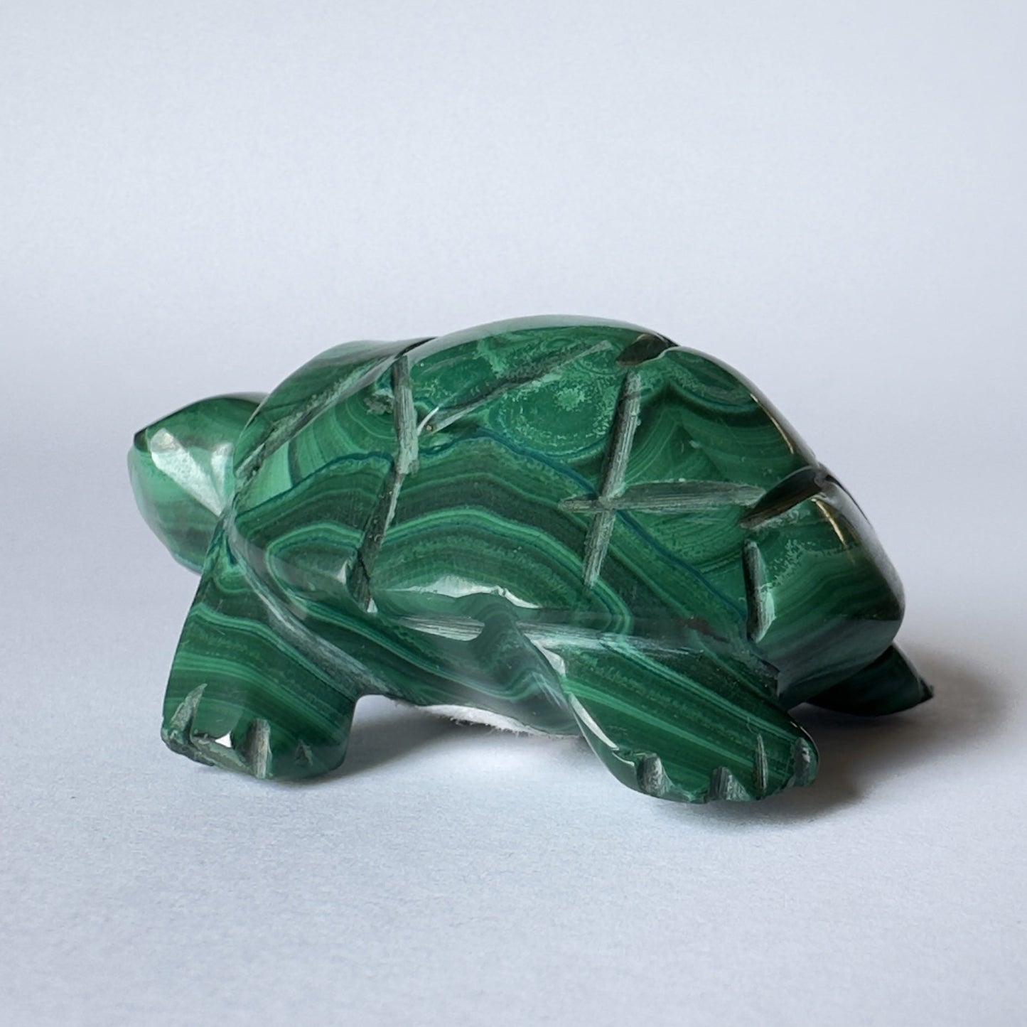 Malakit skildpaddefigur med grønne striber på en lys baggrund.