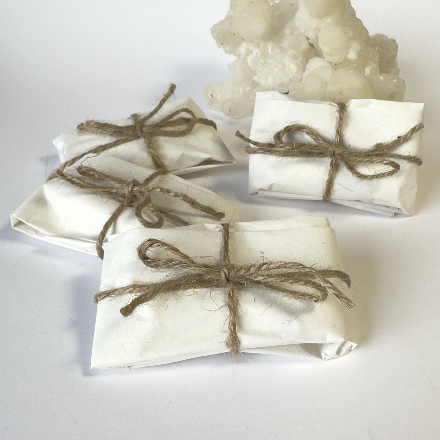 Pakker indpakket i hvidt papir med snore, ved siden af krystaller.