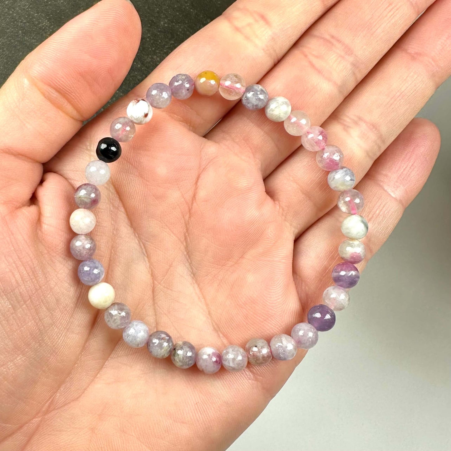 Et armbånd af flerfarvede perler holdes i en hånd.