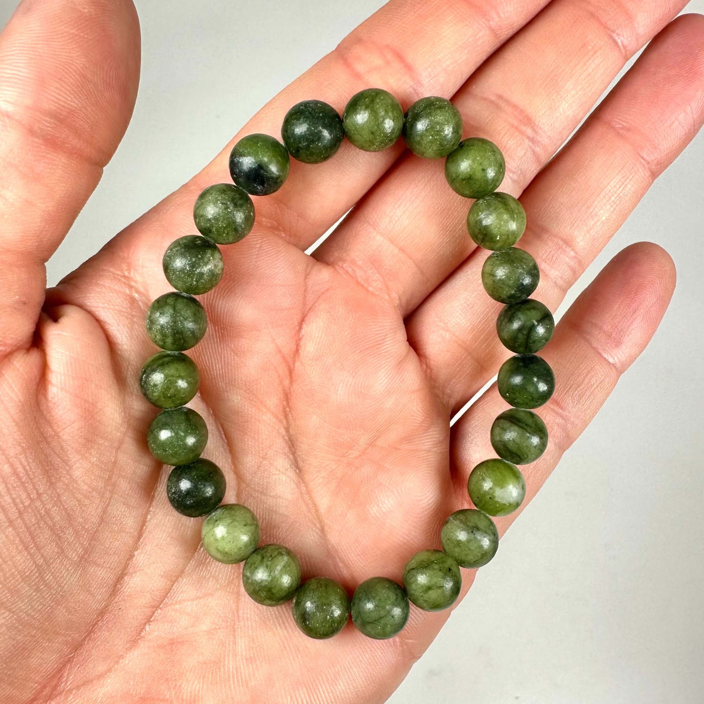 Armbånd med grønne perler holdt i en hånd.