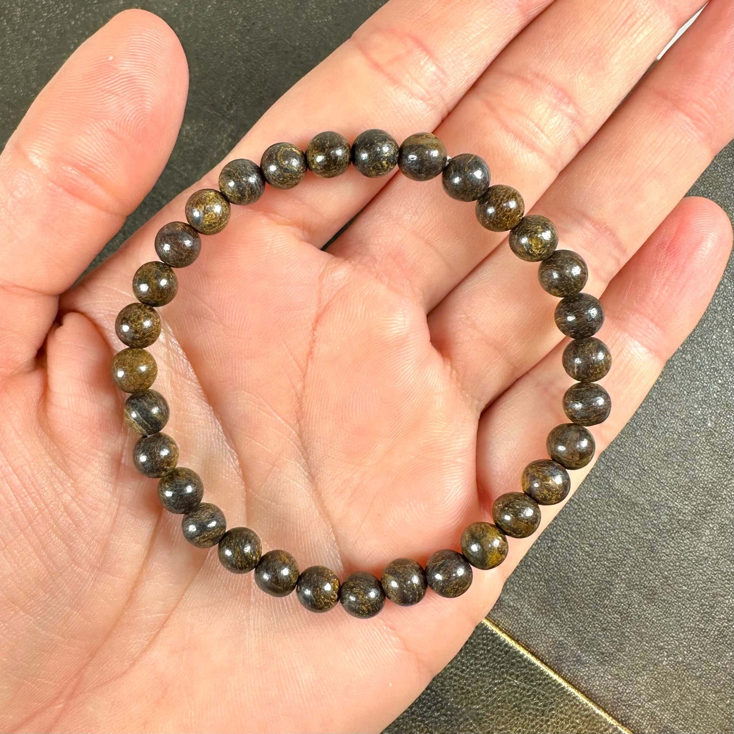 En rundarmbånd med mørke perler hviler i en håndflade.