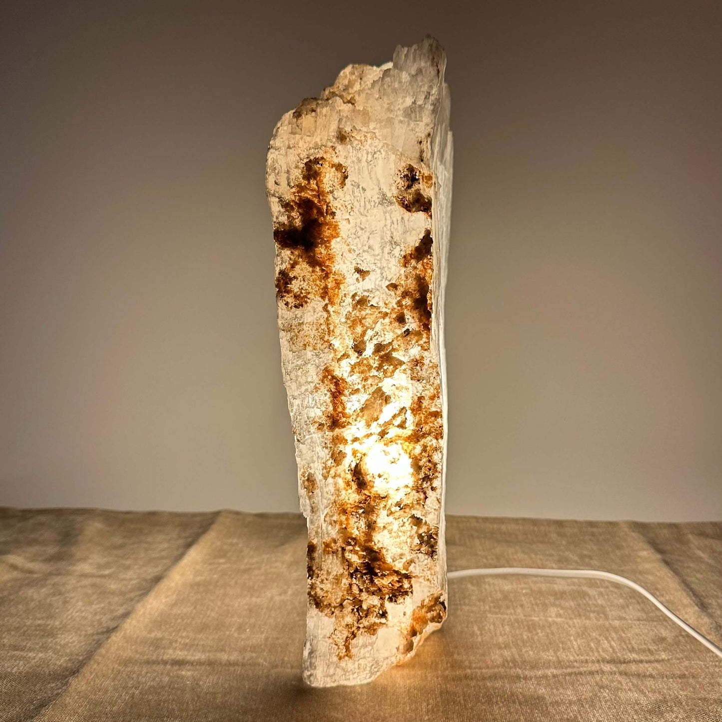 En oplyst saltstenslampe står på et bord, med en blød, varm glød gennem den rustikke overflade.