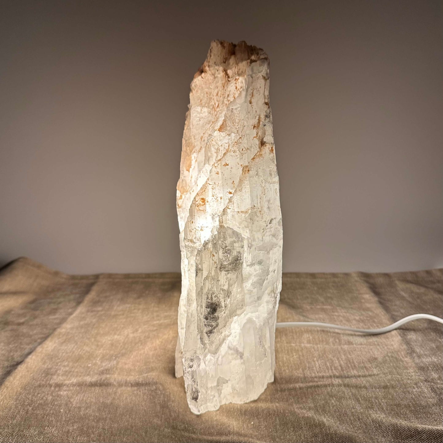 Stenlampe af hvid krystal lyser op på stoffet omkring med en varm glød.