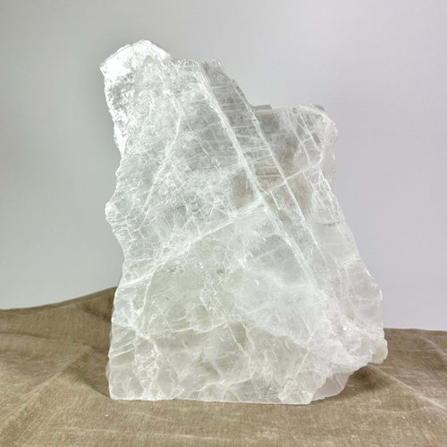 Krystalstruktur med klare, hvide linjer og teksturer, placeret på en beige overflade.