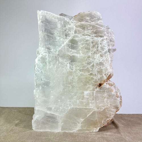 En stor, gennemsigtig krystal med ujævne kanter på en neutral baggrund.