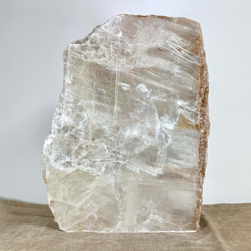 Krystalinsk sten placeret på beige overflade mod grå baggrund.