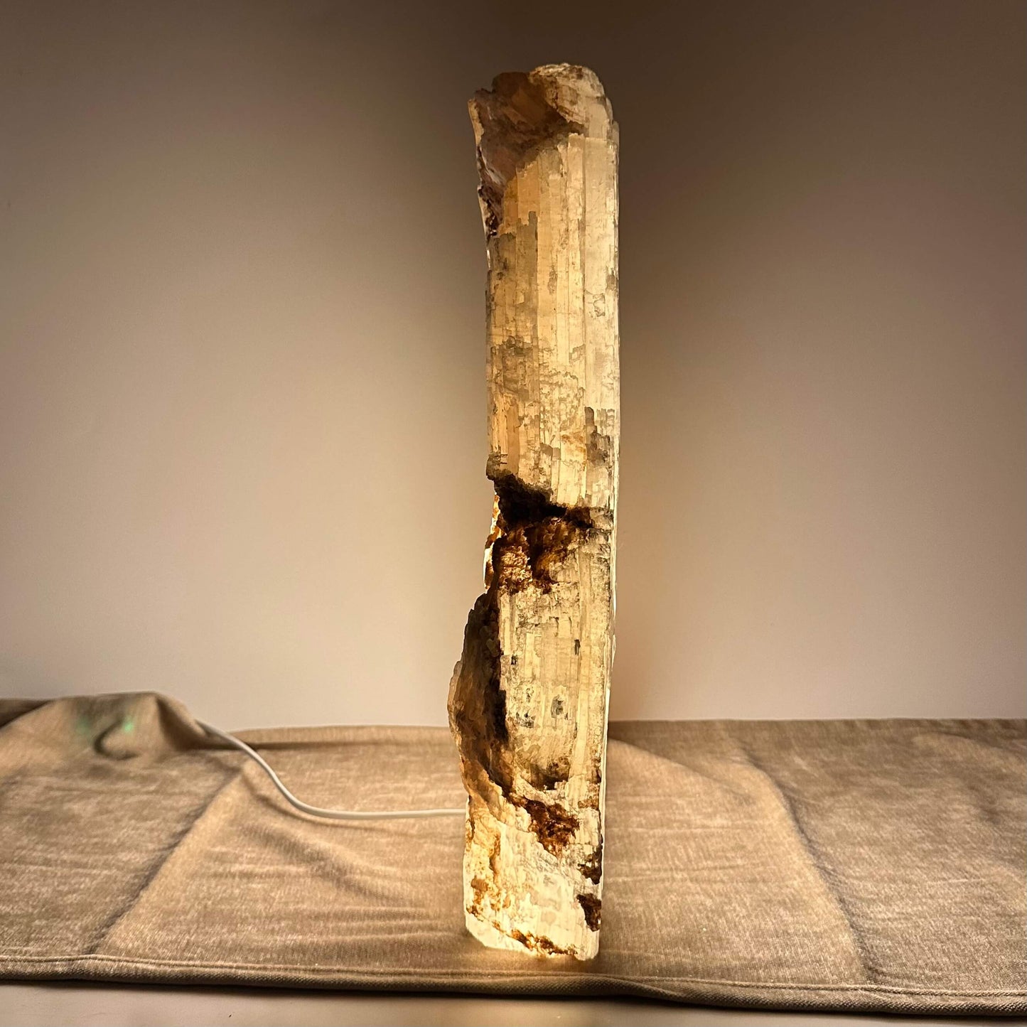 En stearinlysformet saltlampe udsender et varmt, gyldent lys på en neutral overflade.