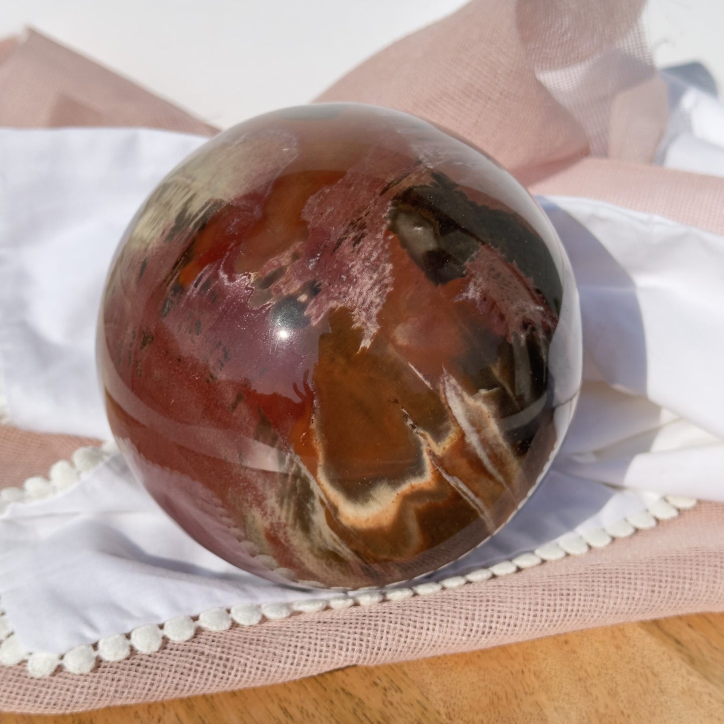 Forstenet træ kugle med brune og røde nuancer på hvidt og lyserødt stof.