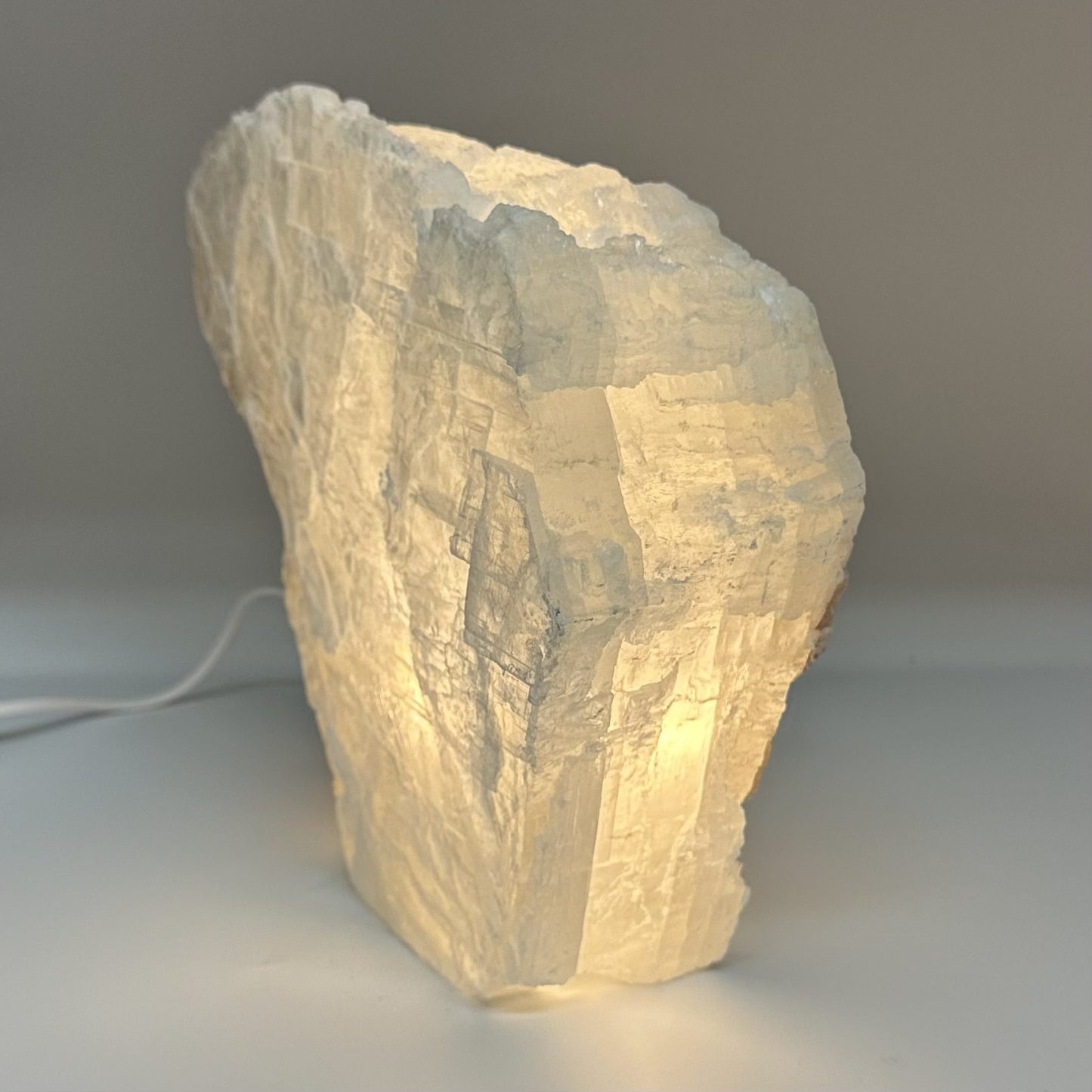 Mexicansk Selenit lampe nr 18 afgiver et blødt, varmt lys gennem den klare krystalstruktur på en simpel baggrund.