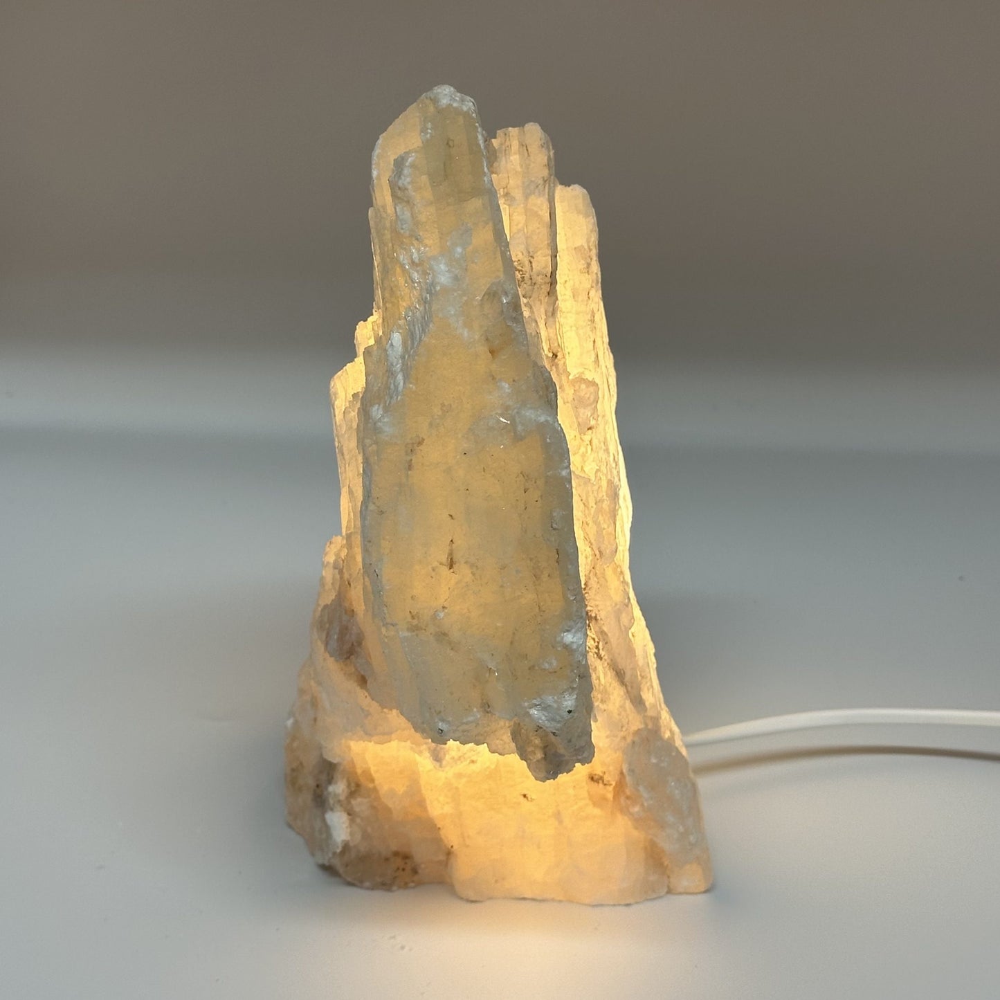 Mexicansk Selenit lampe nr 39 lyser op med en varm glød og fremhæver krystalstrukturen mod en neutral baggrund.