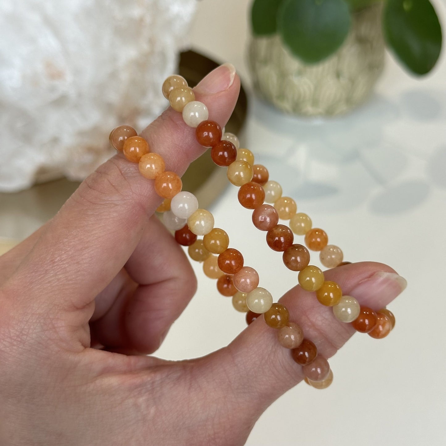 Hånd holder to røde og gule jade armbånd.