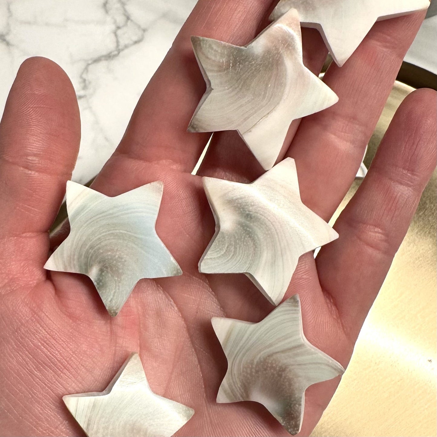 En hånd holder flere stjerneformede sten med et mønster, kendt som Shivas øje stjerne.