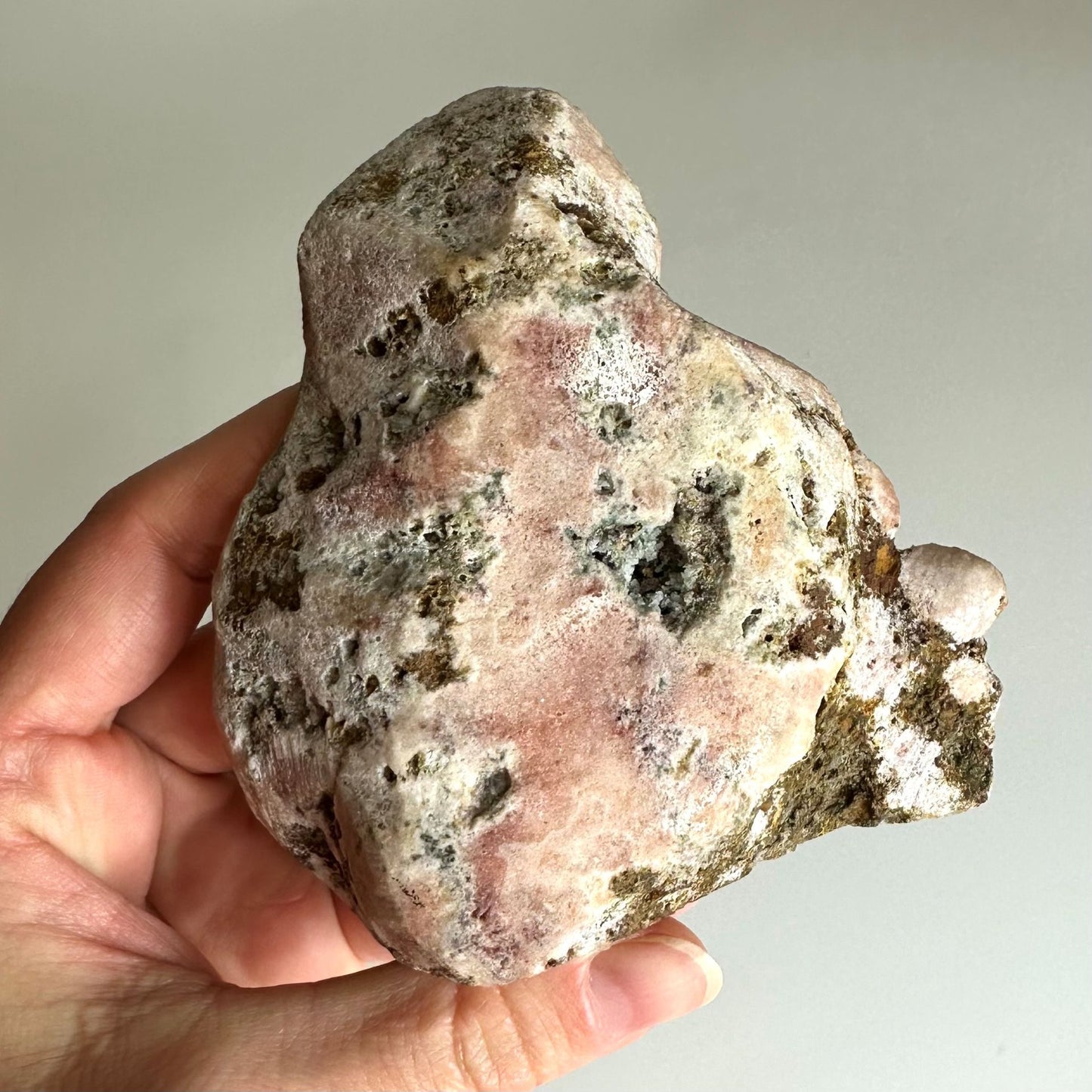 Hånd, der holder Pink Ametyst, unika A3, med rå struktur og naturlige farver.