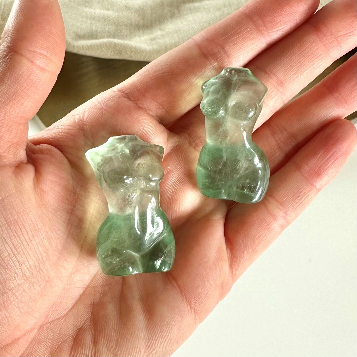 To grønd fluorit torsoer i en hånd, skulptureret som kvindelige figurer.