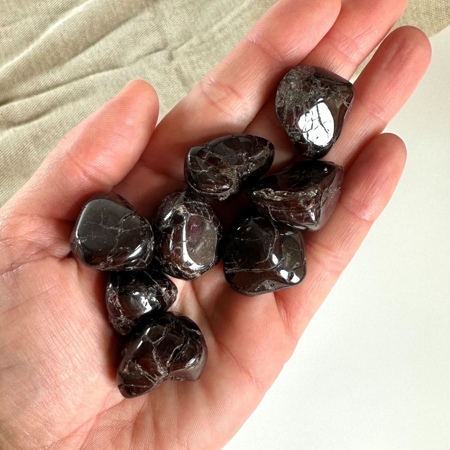 En hånd holder flere Granat lommesten med en dyb rød farve og skinnende overflade.