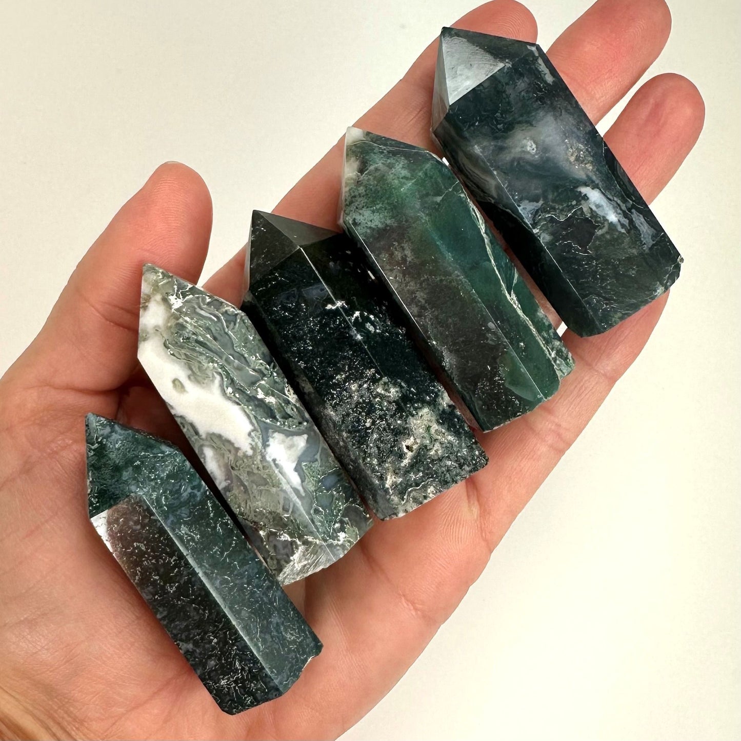 Fem mos agat tårne i en hånd, hver med unikke grønne og hvide mønstre.