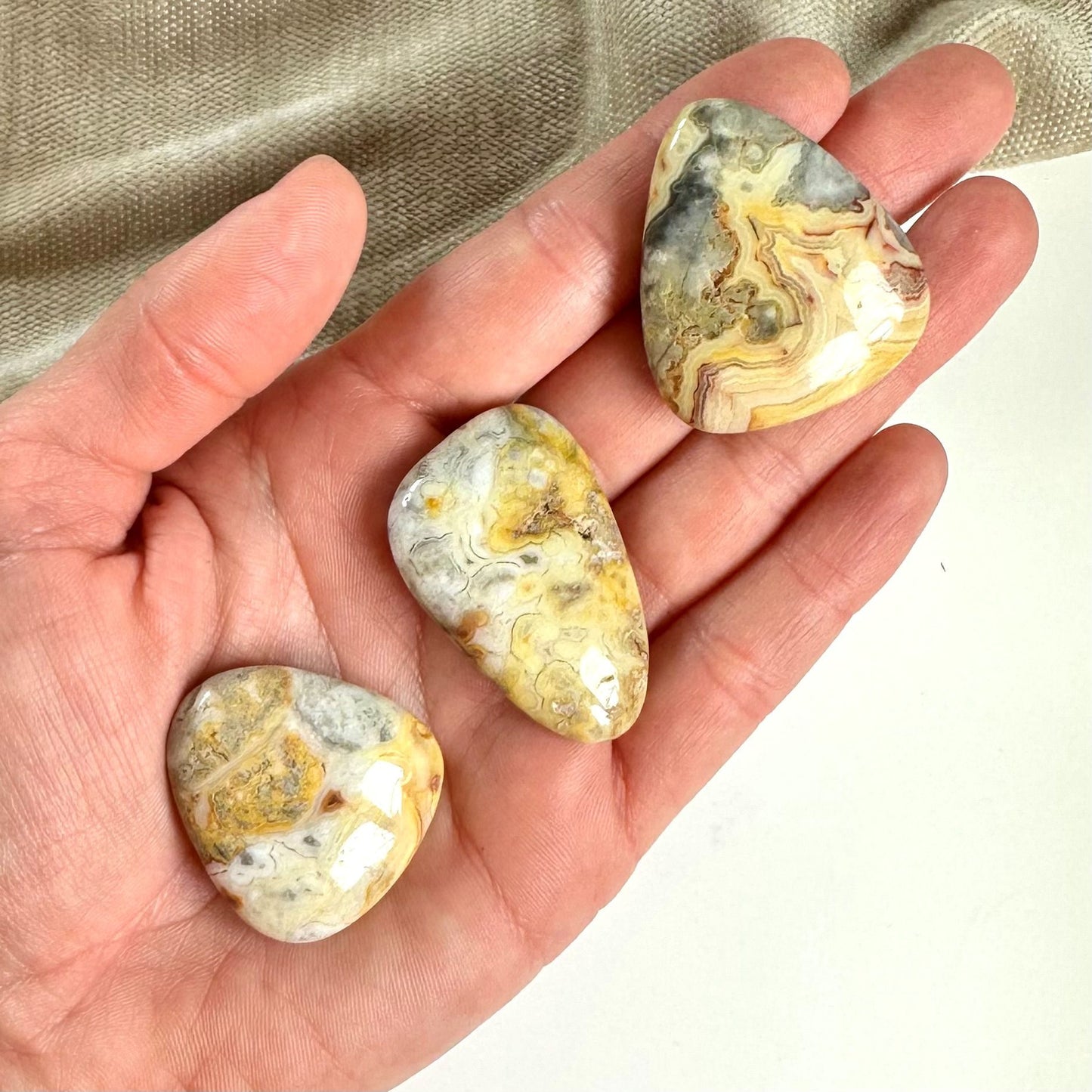 Tre Agat crazy lace-sten i en hånd med varierende mønstre og farver.