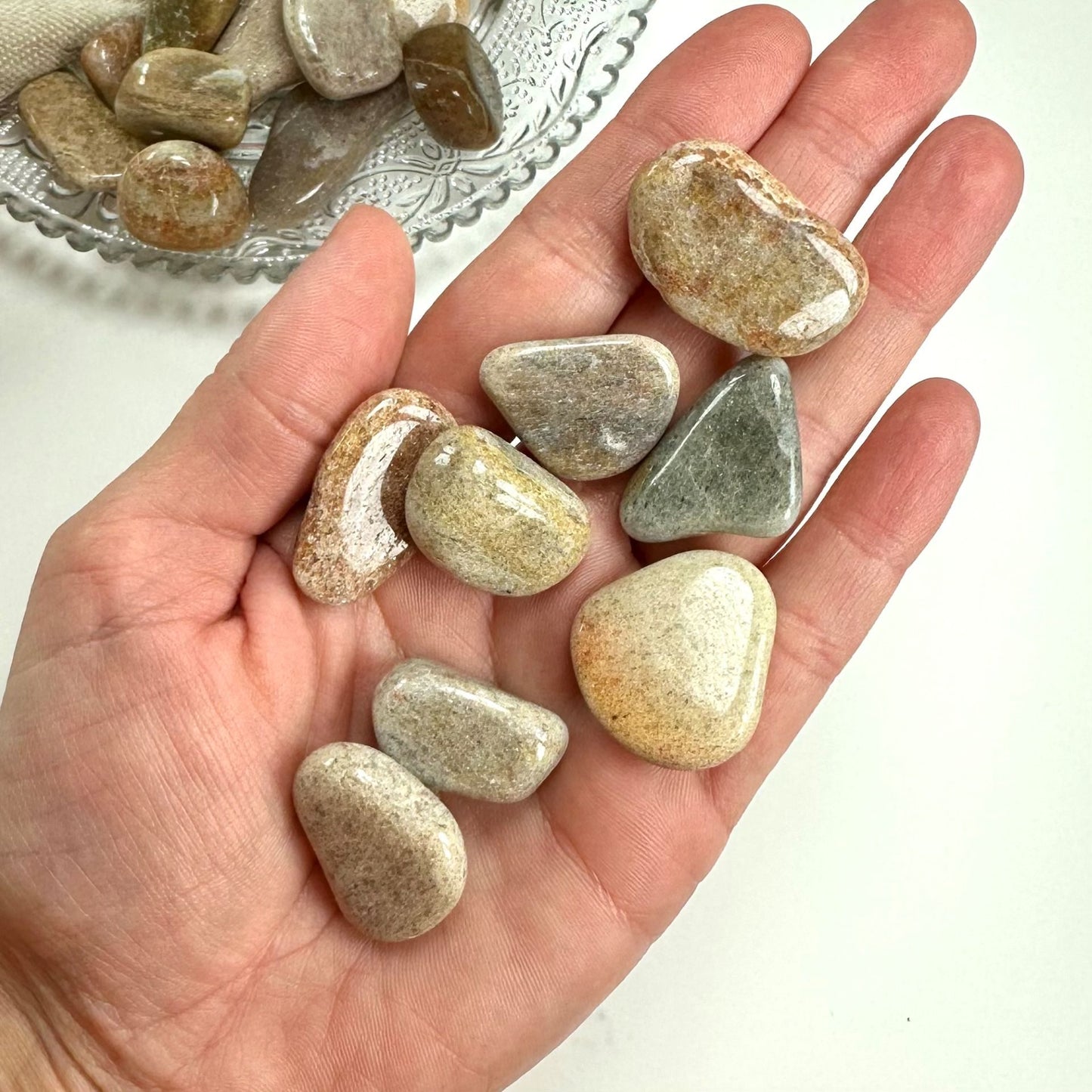 Hånd holder kvartsit karamel sten med varierede nuancer af beige og brun.