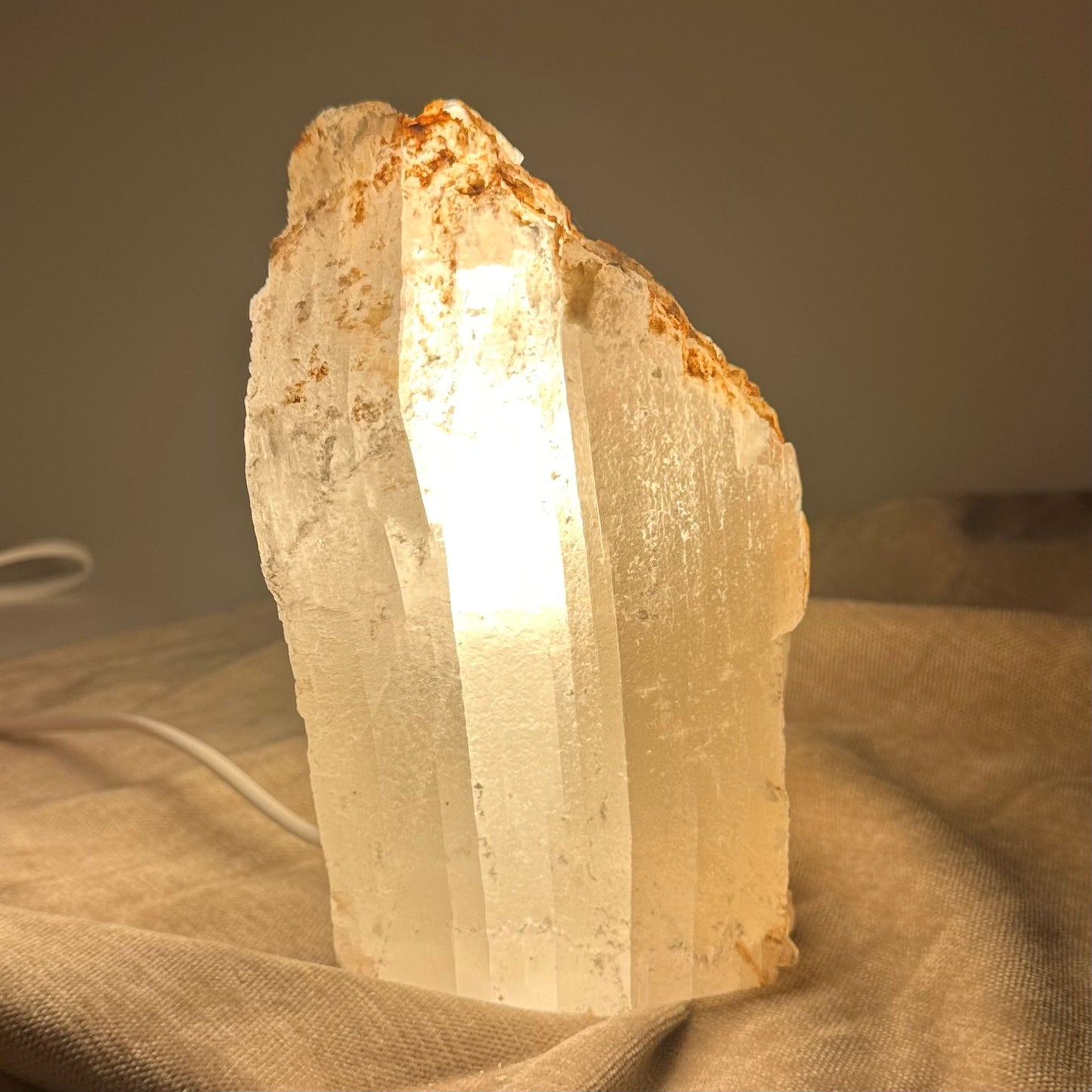 Mexicansk Selenit lampe nr 22 lyser op med varmt skær mod en beige baggrund.