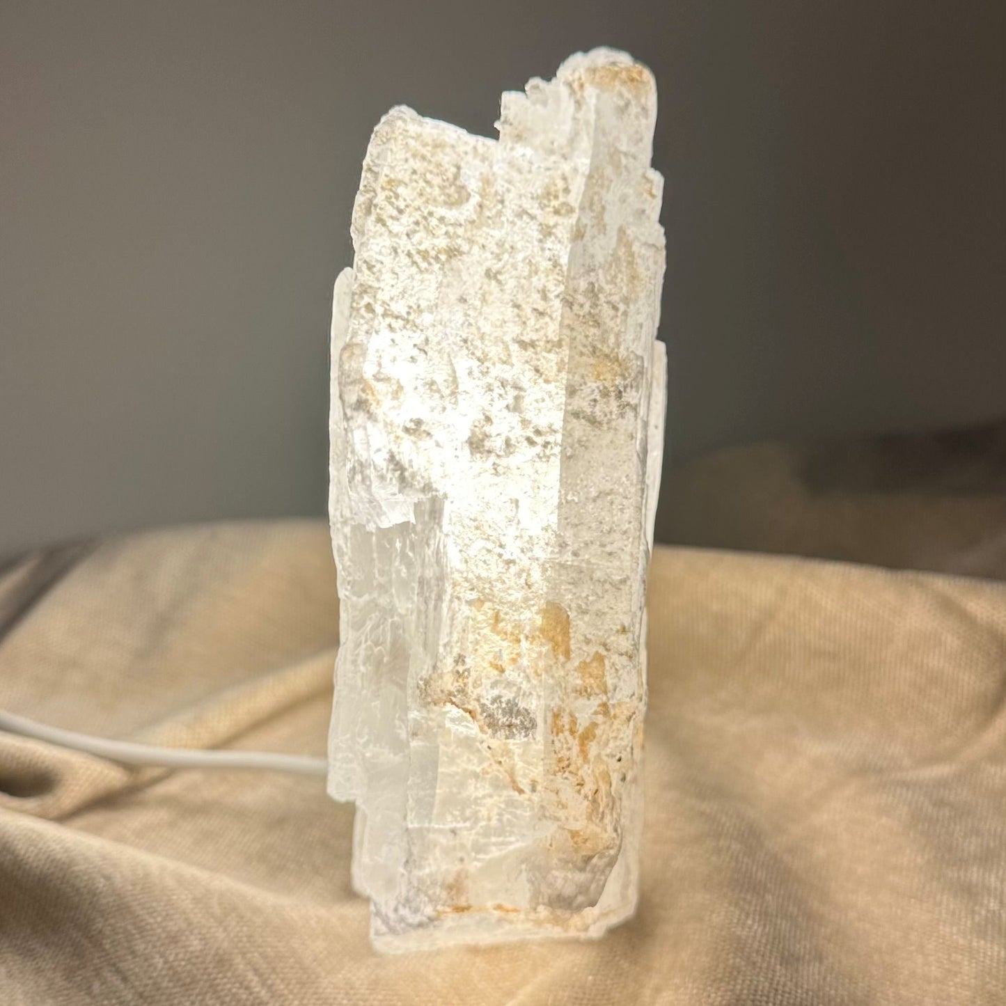 Mexicansk Selenit lampe nr 23 lyser blidt med et varmt skær, placeret på en blød, beige overflade.