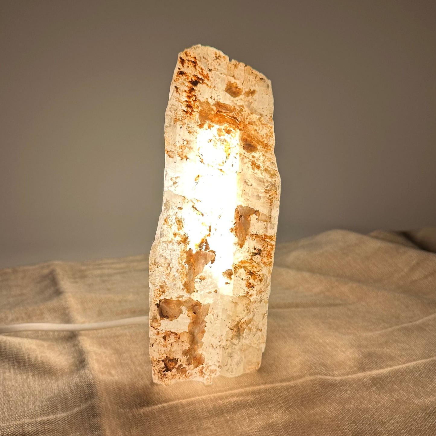 Mexicansk selenit lampe nr 29 lyser op på en beige klud, med en varm glød fra indersiden.