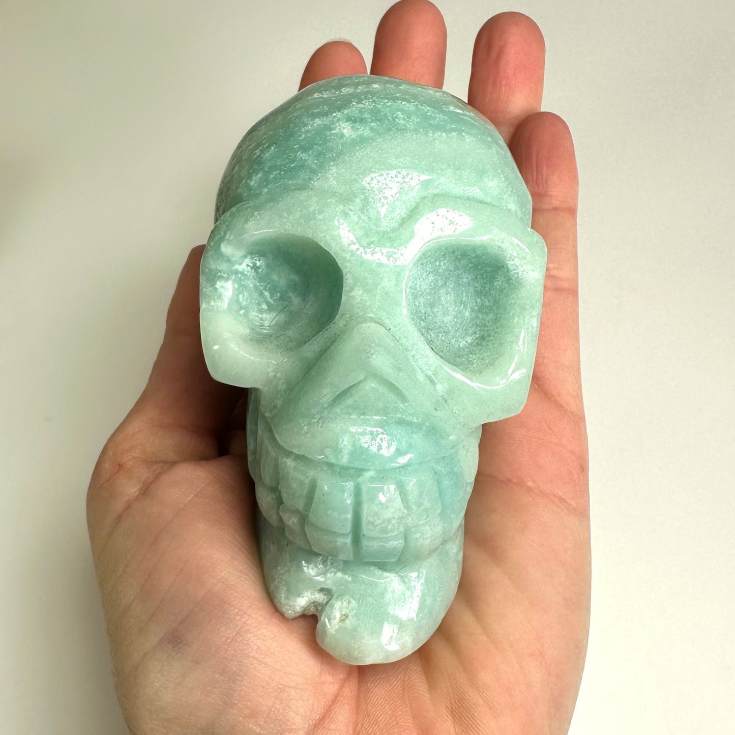 Turkis Amazonit kranium holdt i en hånd.