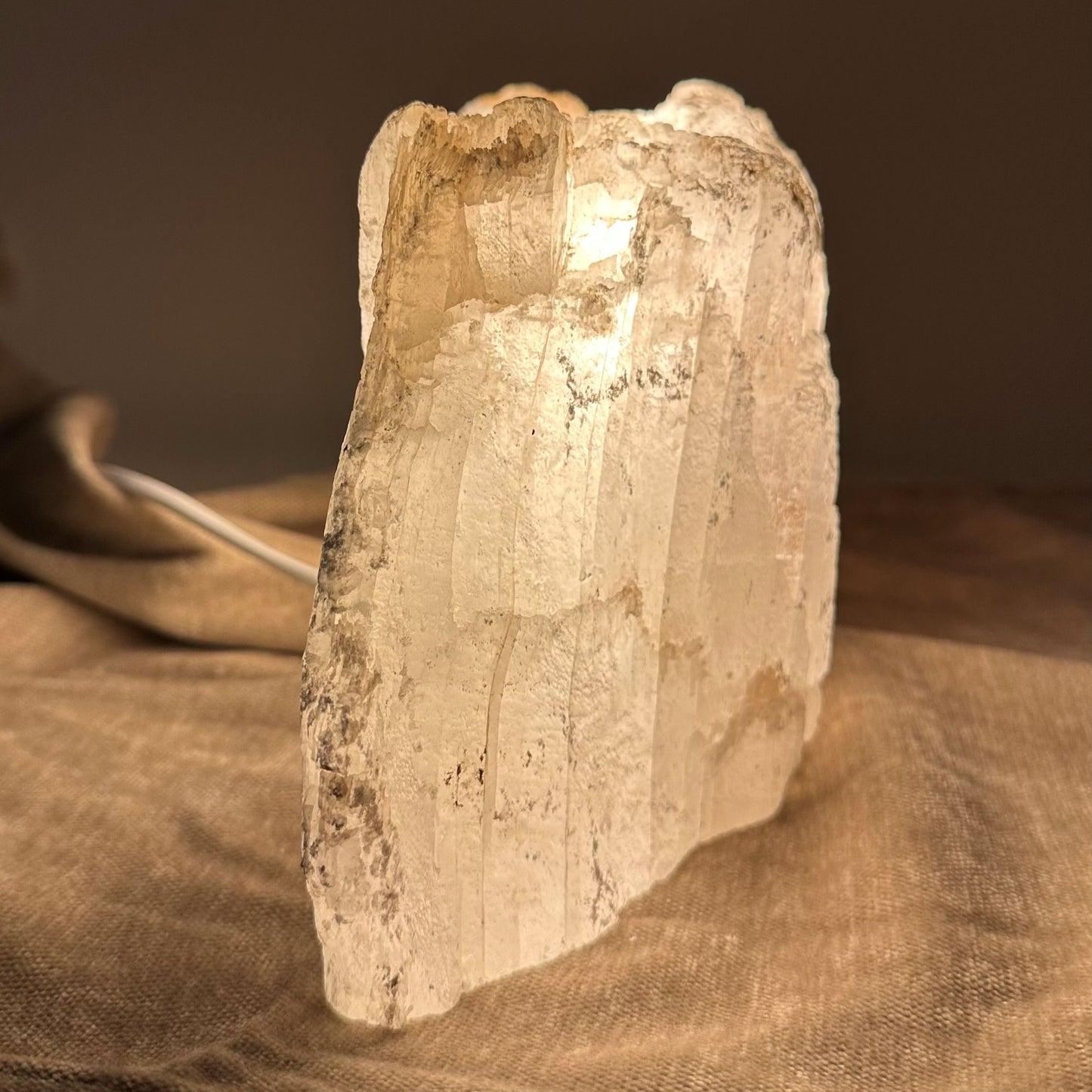 Mexicansk Selenit lampe nr. 42 gløder varmt på stof, skaber en afbalanceret, naturlig atmosfære.