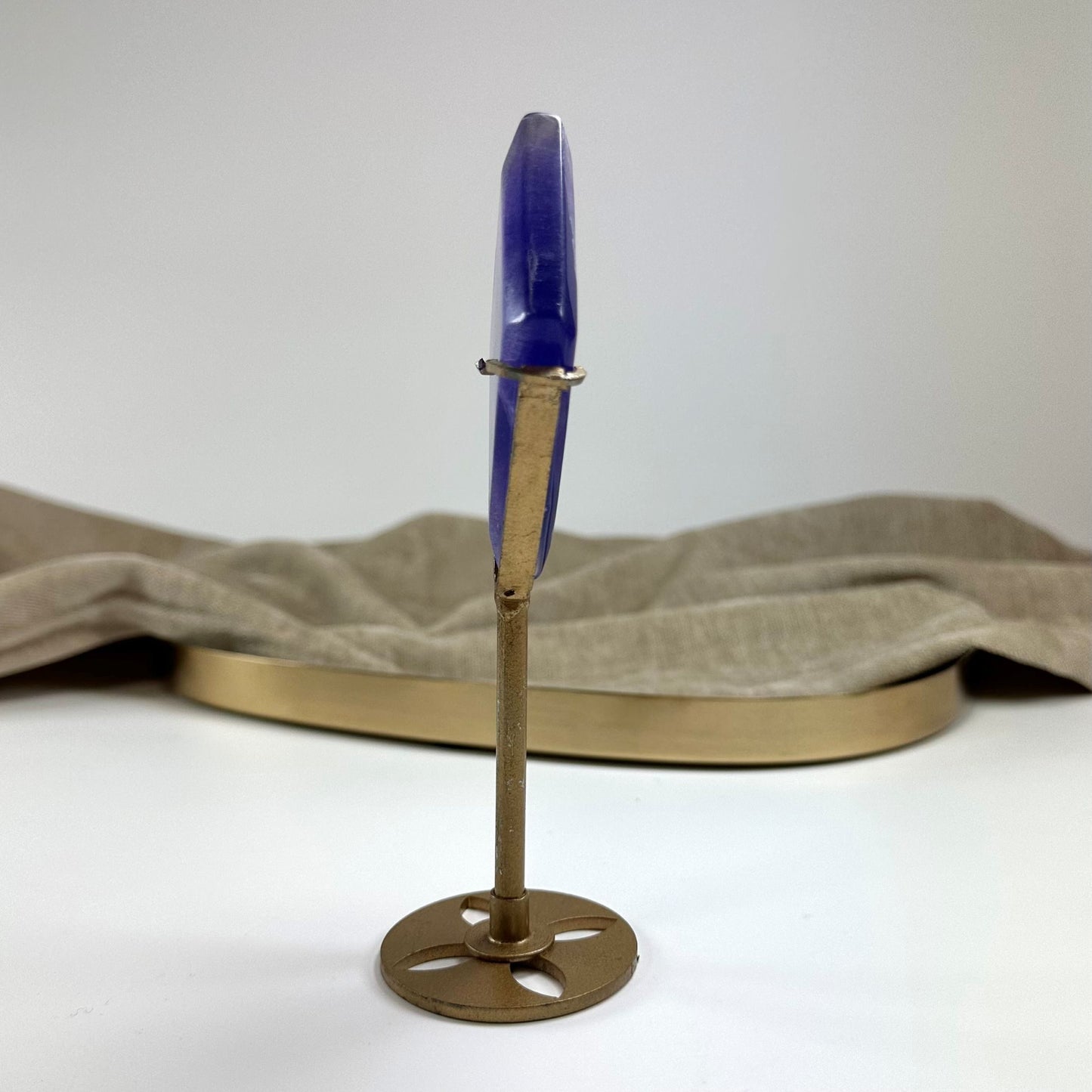 Lilla Fluorit rude på guldfarvet stativ mod en baggrund af beige stof.