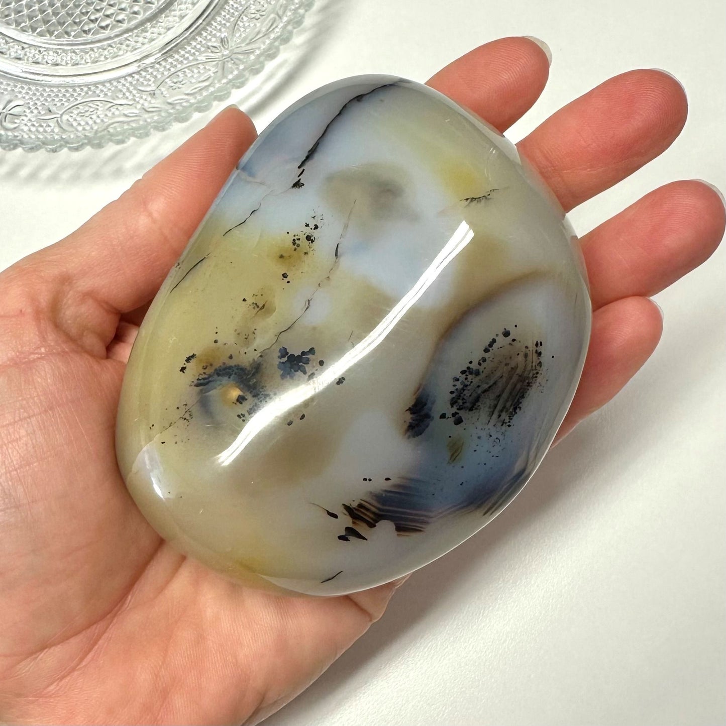 Hånd holder en poleret Agat natur jumbo-sten med mønstre i blå og beige nuancer.