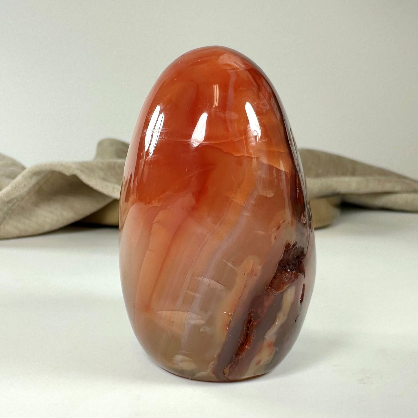 Karneol jumbo-sten med glatte, polerede overflader i varme farvetoner på en lys baggrund.