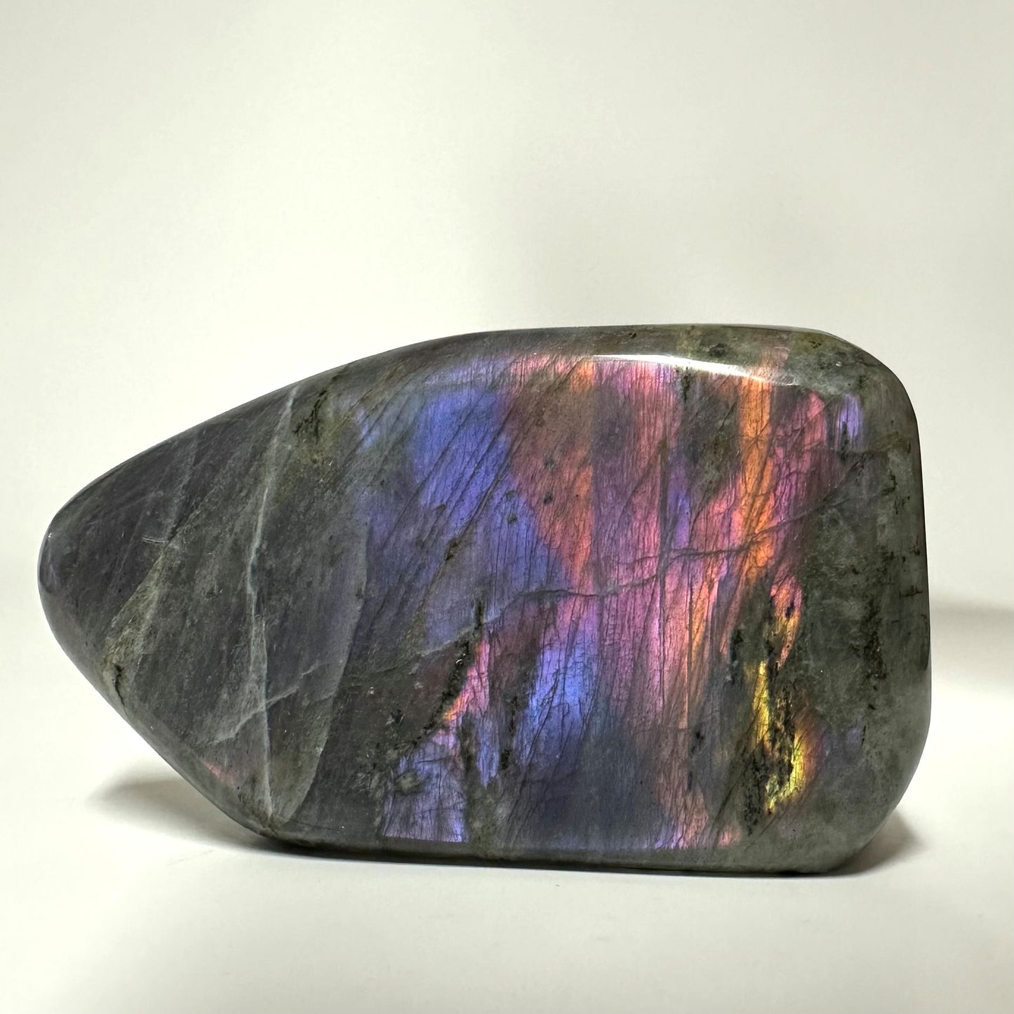 Labradorit sunset free form viser en glitrende overflade i lilla, blå og gyldne nuancer på en blød, poleret sten.